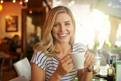 Woman in restaurant holding a coffee cup and smiling