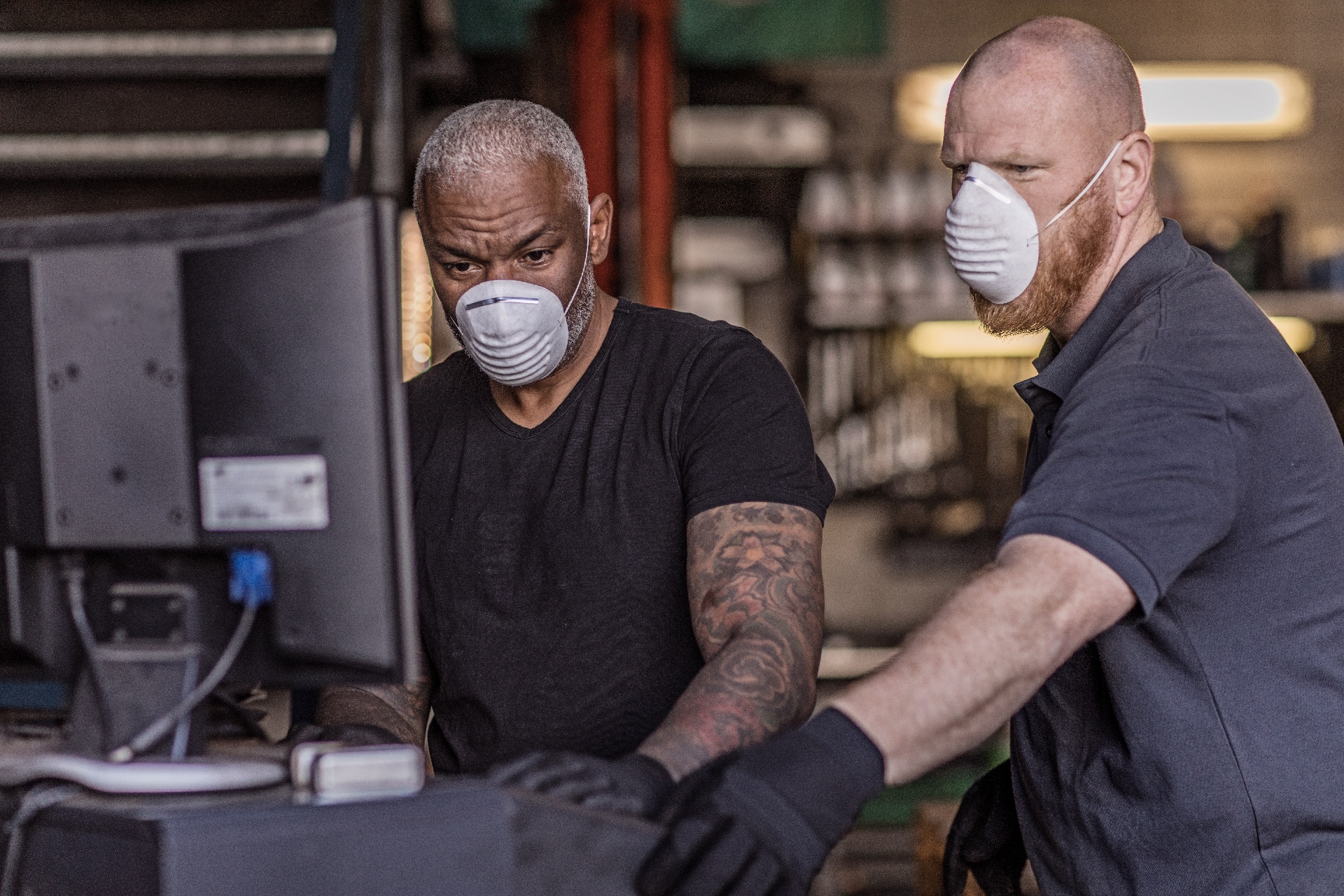 Two essential employees wearing masks at work