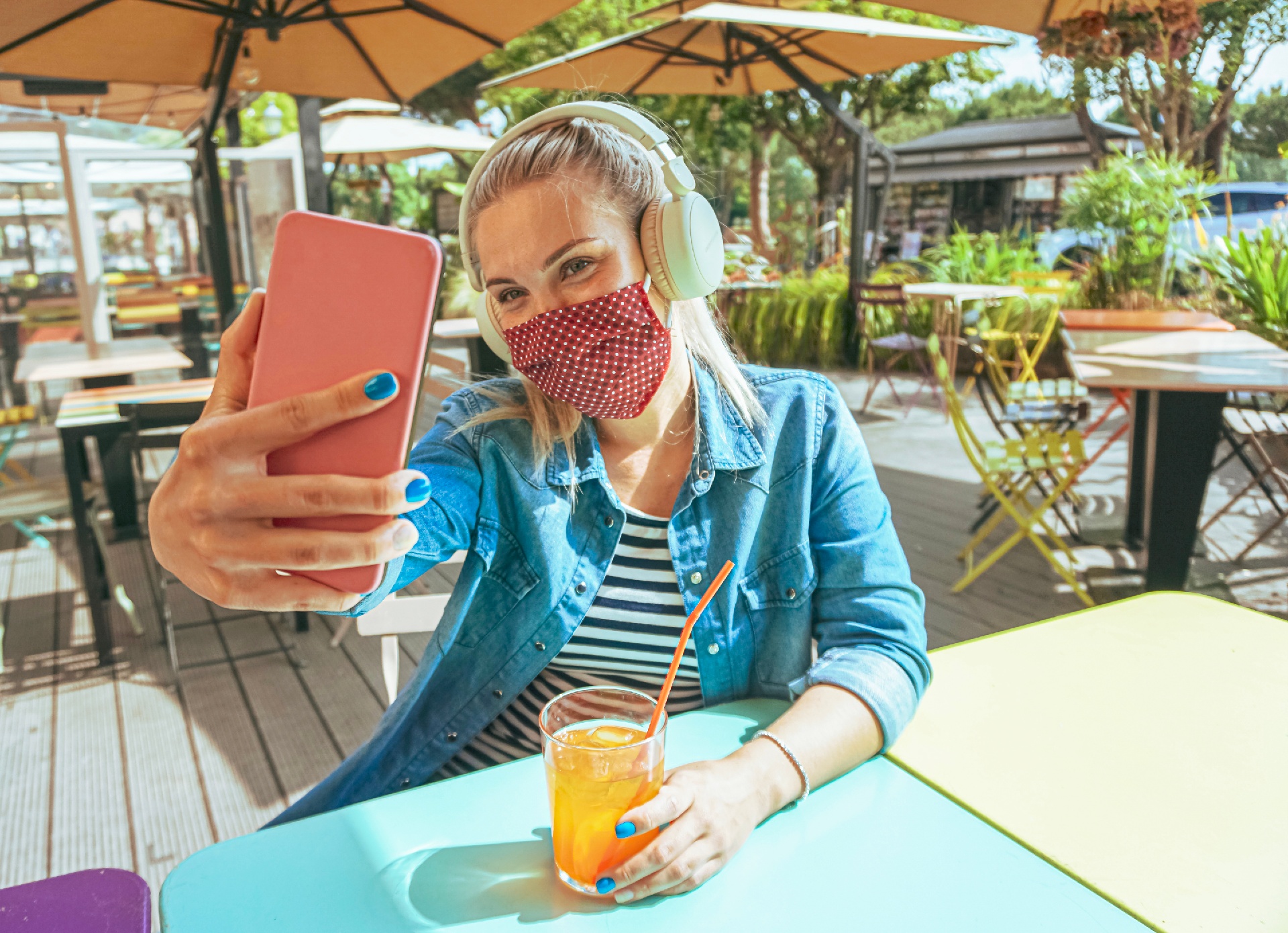 Girl taking selfie with mask at outdoor patio