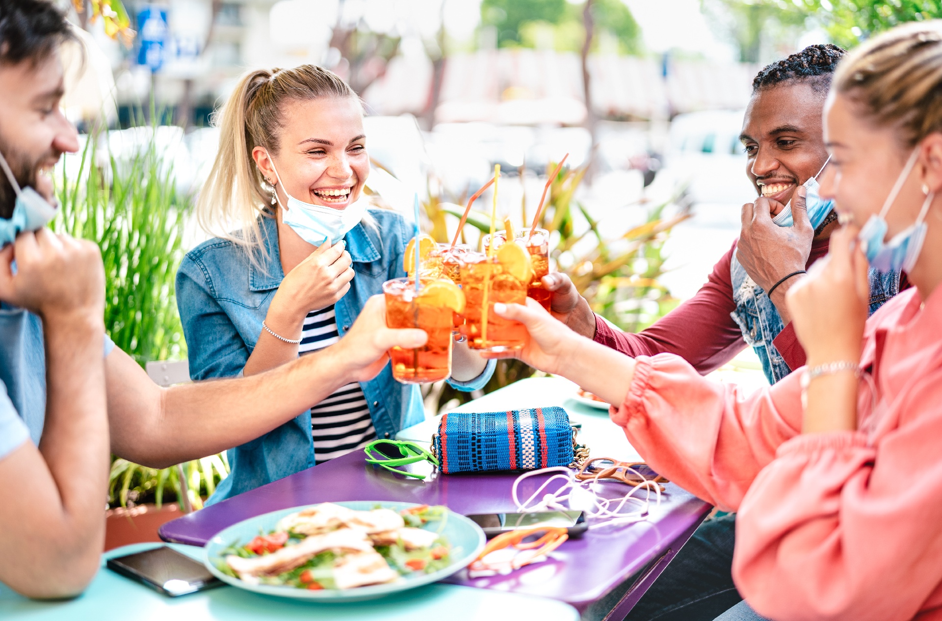 group of friends cheersing drinks and pulling masks down