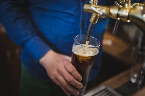 man pouring beer from a tap