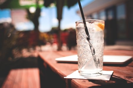 BERNICKS_Water_April17.jpeg glass of water with a straw and lemon sitting outside on a sunny picnic table
