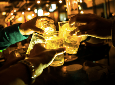 people clinking glasses in front of a gold light