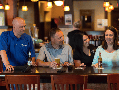 people sitting at a bar table laughing