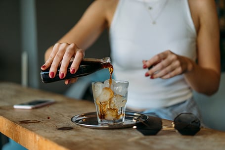 Cold Coffee Being Poured by a Woman into a Glass with Ice