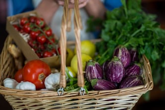 Close-up of female staff holding basket of vegetables in organic section of supermarket