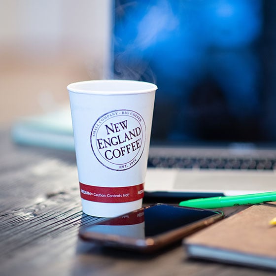 New England Coffee cup next to a computer